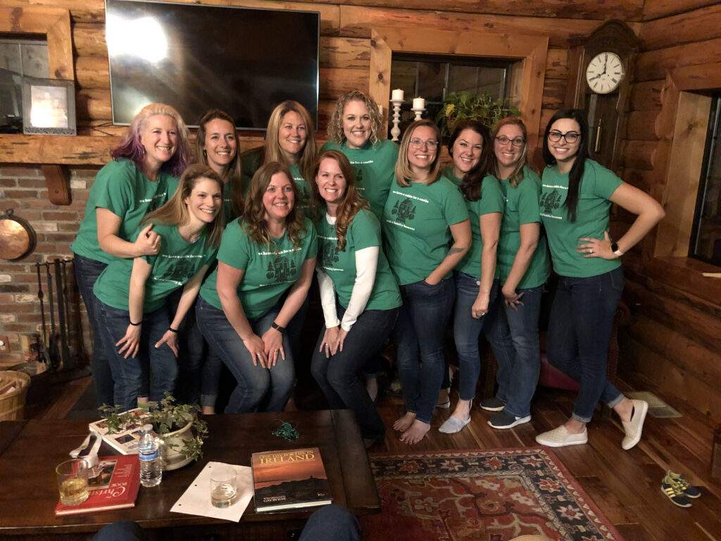 women in green shirts posing in a cabin